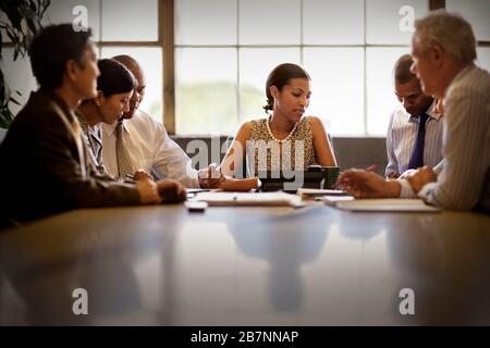 Femme d'affaires de taille moyenne assise dans une salle de réunion avec collègues. Banque D'Images
