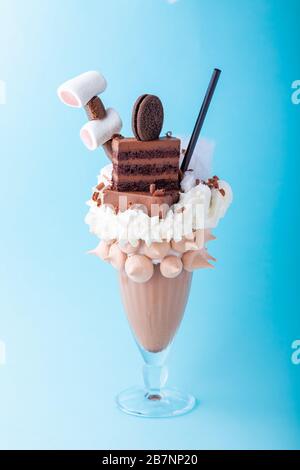 Freakshake au chocolat avec crème fouettée, guimauve, gâteau, cookie en verre avec tubes à cocktail sur fond rose, personne, vue latérale, espace de copie Banque D'Images