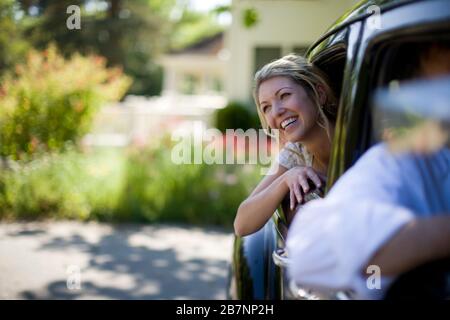 Les jeunes adultes mariée avec sa tête hors de la fenêtre d'une voiture le jour de son mariage. Banque D'Images