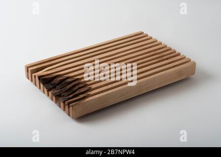 Un trivet en bois fait à la main en érable et en noyer à utiliser sur une table à manger sous des plats chauds. Banque D'Images