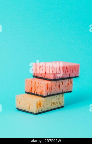 Sur un fond bleu, des éponges colorées pour le lavage de la vaisselle sont disposées par étapes. Banque D'Images