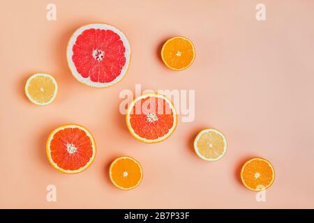 Composition de la couche plate avec les moitiés de différents agrumes sur fond rose. Banque D'Images