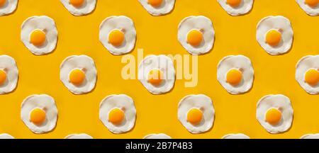 Motif minimaliste créatif au format bannière. Œufs frits sur fond jaune, vue du dessus. Banque D'Images