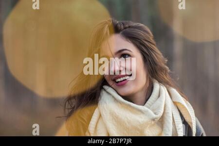 Charmante jeune femme brunette gaie dans un foulard blanc en maille regardant à l'extérieur en automne Banque D'Images
