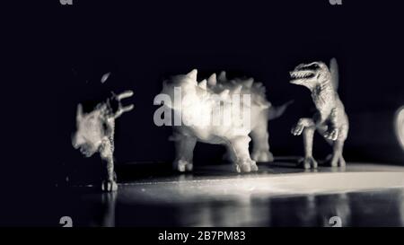 Trois dinosaures jouent ensemble sur la lumière avec un effet noir et blanc Banque D'Images