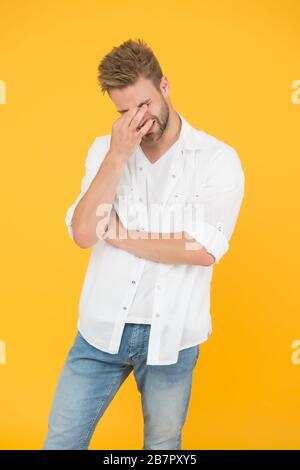 Mal de tête horrible. Bel homme dans un Jean chemise souffrant de douleur de tête. Homme fatigué et stressant fond jaune. Concept de vie stressante. Migraine de tête et spasme. Problèmes de santé. Vie d'affaires. Banque D'Images