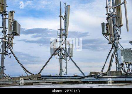 Antenne de réseau de télécommunication radio cellulaire montée sur un poteau métallique fournissant de fortes ondes de signal du haut du toit à travers la grande ville Banque D'Images