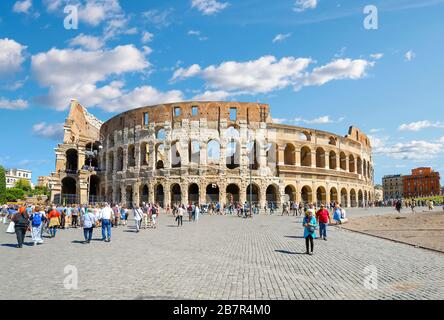 Les touristes passent devant l'ancien Colisée romain lors d'une journée d'été ensoleillée à Rome, en Italie. Banque D'Images