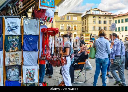 Les touristes et les guides touristiques achètent des souvenirs et parlent avec des vendeurs et des commerçants locaux sur un marché extérieur sur la Piazza Santa Croce à Florence, en Italie. Banque D'Images