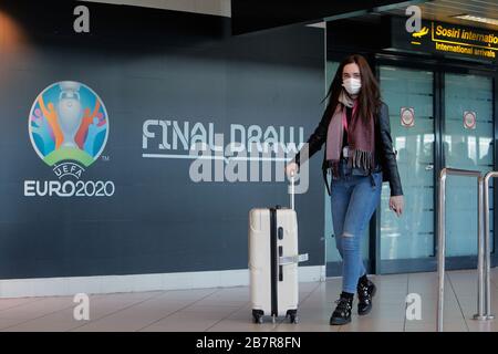 (200318) -- BUCAREST, le 18 mars 2020 (Xinhua) -- une femme portant un masque de visage passe par un logo du championnat européen DE football EURO 2020 exposé sur un mur à l'aéroport international Henri Coanda de Bucarest, Roumanie, le 17 mars 2020. L'organe directeur européen du football de l'UEFA a décidé de reporter le championnat d'Europe de cet été à 2021 en raison de l'épidémie de coronavirus. Le président roumain Klaus Iohannis a annoncé que le pays entrera dans un état d'urgence à partir du 16 mars, dans un effort pour s'assurer que le gouvernement utilise toutes les ressources pour lutter contre l'épidémie de COVID-19. (Photo par Cr Banque D'Images