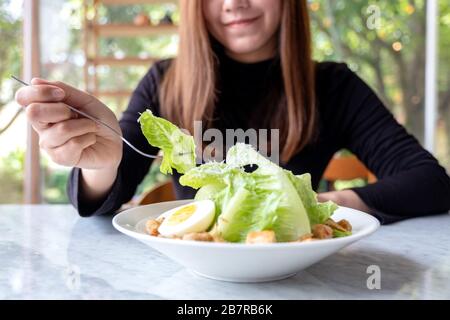 Gros plan image d'une femme mangeant une salade césar à la fourche sur la table dans le restaurant Banque D'Images
