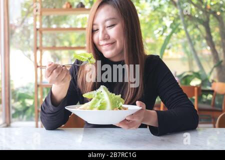 Une belle femme asiatique aime manger de la salade césar sur la table au restaurant Banque D'Images