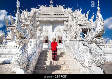 Femme en chemise rouge devant Wat Rong Khun le Temple Blanc à Chiang Rai, Thaïlande Banque D'Images