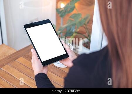 Mockup image d'une femme tenant et regardant un Tablet pc noir avec un écran blanc vide Banque D'Images