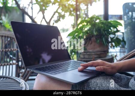 Gros plan sur les mains de la femme en utilisant et en touchant le pavé tactile de l'ordinateur portable tout en étant assis à l'extérieur Banque D'Images