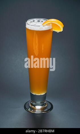 Grand verre de bière blanche non filtrée avec une glace d'orange sur un fond noir. La bière est l'une des plus anciennes, les plus populaires et les plus largement consommés Banque D'Images