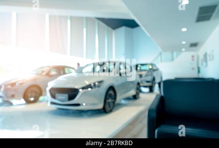 Vue avant floue de la voiture blanche et du client. Nouvelle voiture de luxe stationnée dans une salle d'exposition moderne. Bureau de la concession automobile. Concept d'entreprise automobile électrique. Auto Banque D'Images