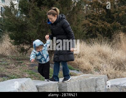 Une mère a aidé sa fille à clamber sur quelques grandes pierres dans le parc de la rivière Hudson. Le parc longe la rivière Hudson entre Chambers Street et MID Banque D'Images