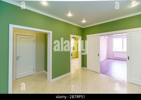 Couloir vide avec murs verts et sol en marbre dans un nouvel appartement avec une rénovation fraîche. Les portes mènent du hall aux différentes chambres Banque D'Images