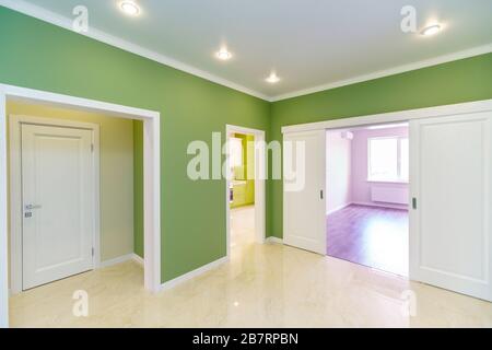 Couloir vide avec murs verts et sol en marbre dans un nouvel appartement avec une rénovation fraîche. Les portes mènent du hall aux différentes chambres Banque D'Images