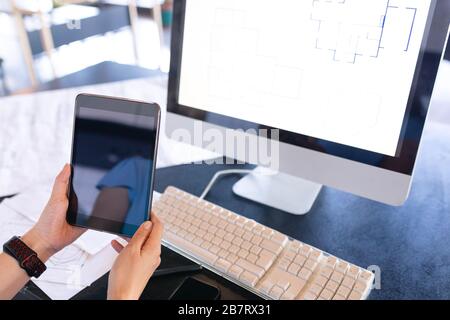 Femme au travail sur ordinateur et la tenue d'une tablette numérique Banque D'Images