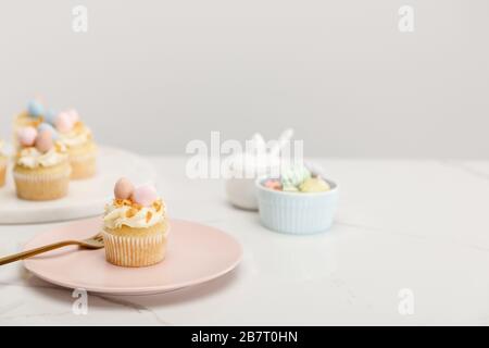 Foyer sélectif des cupcakes de pâques sur plaque et plateau rond près de la cuvette de sucre sur fond gris Banque D'Images