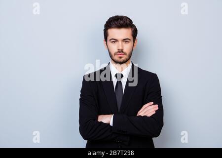 Portrait de beau employeur strict dans des vêtements officiels debout avec des mains croisées contre fond gris Banque D'Images