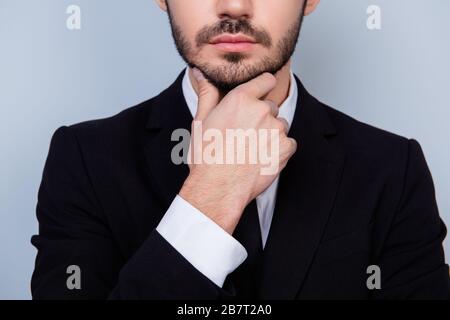 Gros plan photo d'un homme sérieux et confiant dans une chemise blanche et une veste noire touchant son menton Banque D'Images