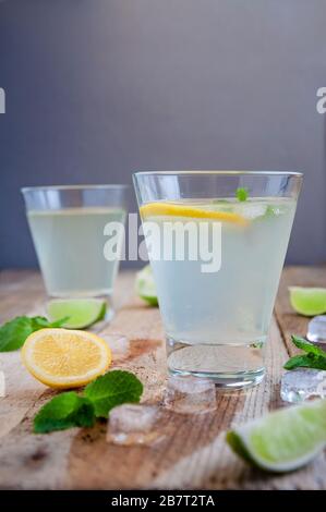 Cocktails rafraîchissants d'été avec glace aux fruits d'agrumes et menthe sur table en bois. Banque D'Images