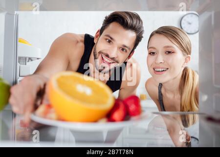 foyer sélectif de l'homme et de la femme heureux regardant des fruits savoureux dans le réfrigérateur Banque D'Images