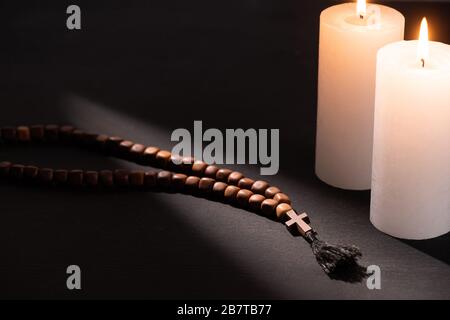 rosary sur fond noir sombre avec bougies brûlantes Banque D'Images