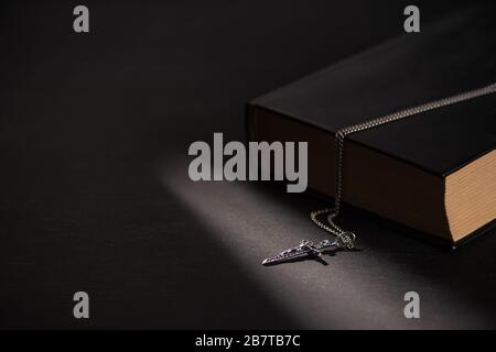 sainte bible avec croix sur fond noir sombre avec bougies brûlantes Banque D'Images