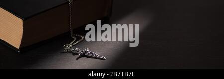 sainte bible avec croix sur fond noir sombre avec bougies brûlantes, photo panoramique Banque D'Images