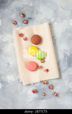 Différents types de macarons et de fleurs roses sur fond de béton. Vue de dessus. Style plat. Banque D'Images