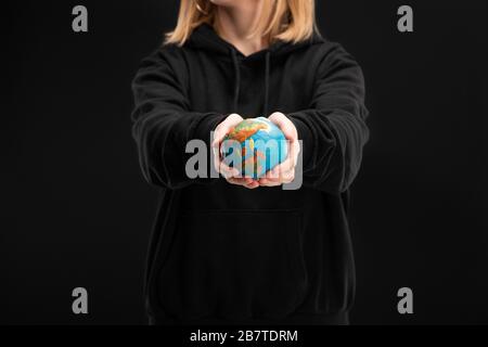 Vue rognée d'une femme avec des mains étirées tenant le globe de plastine isolé sur le concept de réchauffement climatique noir Banque D'Images