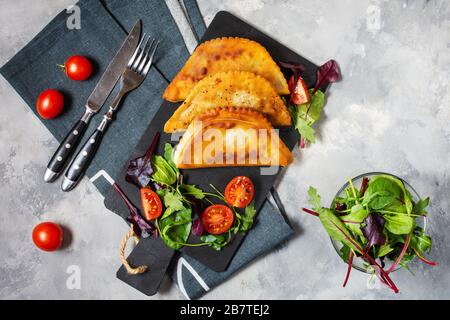 Cuisine latino-américaine, mexicaine et chilienne. Pâtisseries traditionnelles épanadas avec viande de boeuf sur fond de béton. Vue de dessus Banque D'Images