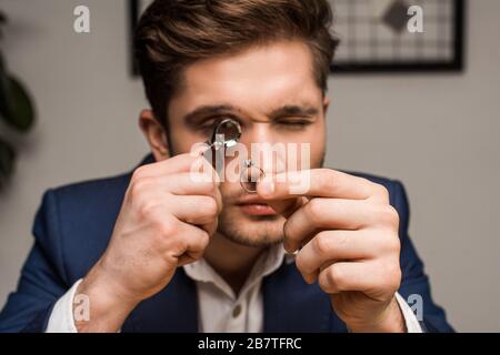 Expert en bijoux avec loupe examinant la bague de bijoux avec pierre gemme en atelier Banque D'Images