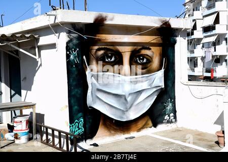 Athènes, Grèce - 17 mars 2020: Un jeune homme fait un graffiti inspiré par les mesures contre le coronavirus (COVID-19) sur la terrasse d'un bloc de Banque D'Images