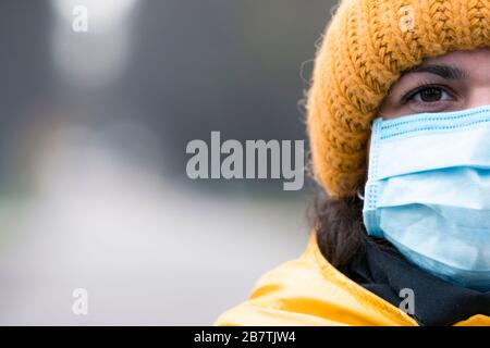 Portrait gros plan jeune européenne femme dans un masque médical jetable de protection marchant à l'extérieur. Nouveau coronavirus (COVID-19). Concept de voiture de santé Banque D'Images