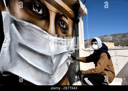 Athènes, Grèce - 17 mars 2020: Un jeune homme fait un graffiti inspiré par les mesures contre le coronavirus (COVID-19) sur la terrasse d'un bloc de Banque D'Images