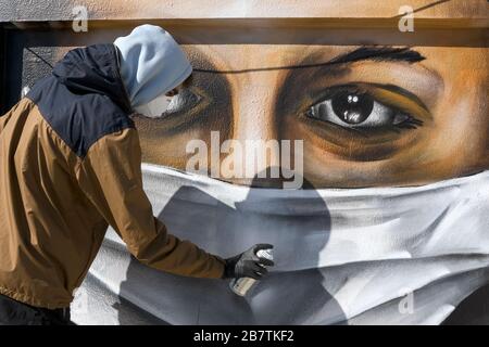 Athènes, Grèce - 17 mars 2020: Un jeune homme fait un graffiti inspiré par les mesures contre le coronavirus (COVID-19) sur la terrasse d'un bloc de Banque D'Images