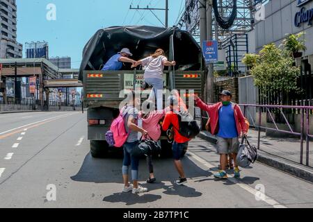 Makati City. 18 mars 2020. Les gens montent un camion militaire offrant des manèges gratuits aux navetteurs bloqués après que le gouvernement philippin a ordonné la suspension des installations de transport en commun de masse conformément à la « quarantaine communautaire renforcée » à Makati City, aux Philippines, le 18 mars 2020. Crédit: Rouelle Umali/Xinhua/Alay Live News Banque D'Images