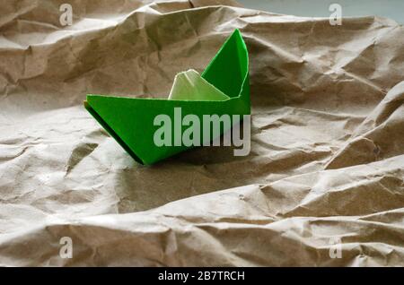 Bateau en papier à base de papier de merde. Origami du papier vert coincé et déchiré. Un concept contre tout pour atteindre un objectif. Prise de vue au niveau des yeux. Côté vi Banque D'Images