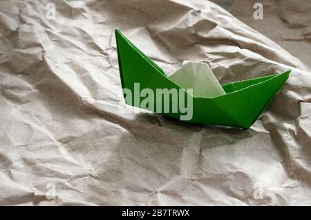 Vue rapprochée de l'ancien bateau en papier. Origami du papier vert coincé et déchiré. Concept ne jamais abandonner. Prise de vue au niveau des yeux. Vue latérale. Mise au point sélective. Banque D'Images