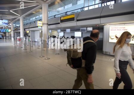 Berlin, Allemagne. 18 mars 2020. Deux passagers portant un masque de visage marchent devant des comptoirs d'enregistrement vides dans le terminal de l'aéroport de Tegel. Crédit: Wolfgang Kumm/dpa/Alay Live News Banque D'Images