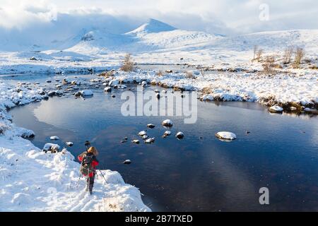 Photographe en hiver froid après-midi avec loch partiellement gelé et neige au Loch Ba, Rannoch Moor, Argyll et Bute, Ecosse en janvier Banque D'Images