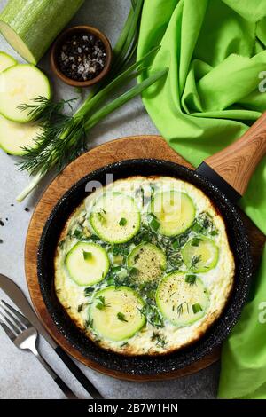 Petit déjeuner. Omelette d'été avec courgettes et herbes sur une table en pierre ou en ardoise. Vue sur le dessus plat. Banque D'Images