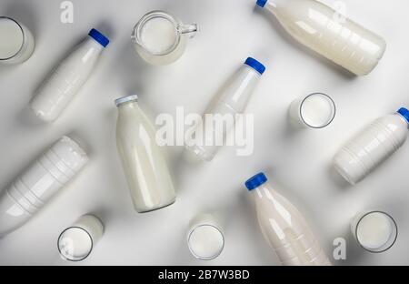 Emballage des produits laitiers, bouteilles et verres avec lait sur fond blanc, vue du dessus Banque D'Images