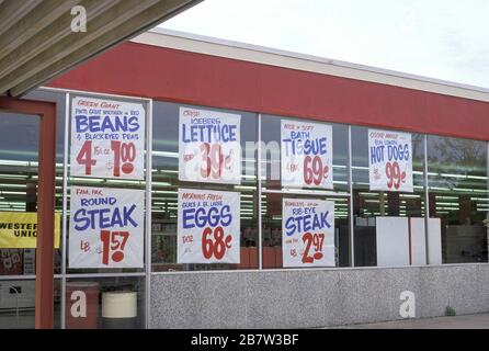 Affiches de prix des aliments à la fenêtre du petit supermarché. ©Bob Daemmrich Banque D'Images