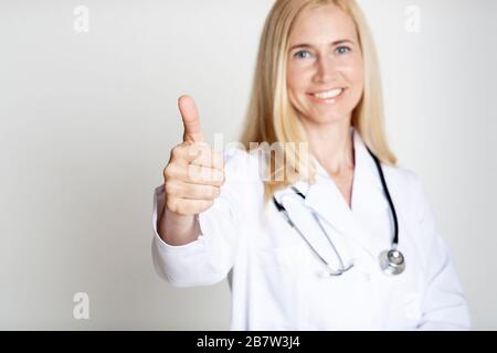 Bonne femme mûre médecin en uniforme avec le pouce vers le haut Banque D'Images